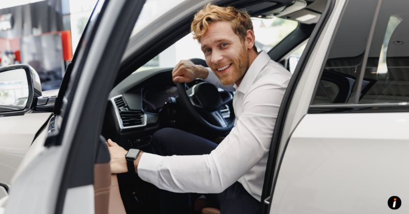 a man smiling in a brand new rental car