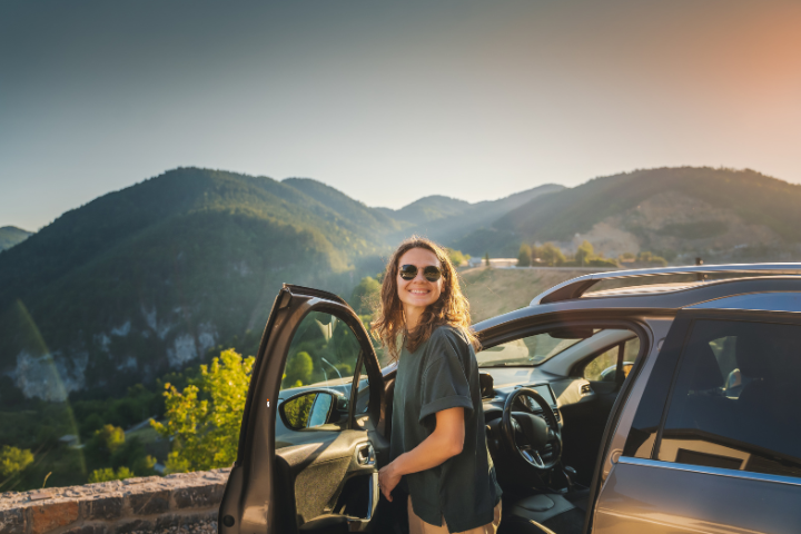 a woman smiling in front of her car